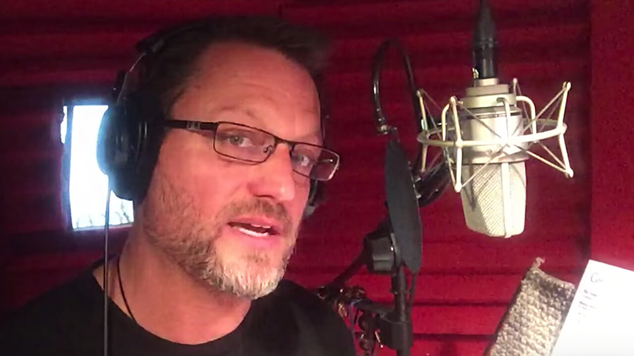 Steve Blum at the microphone with red foam behind