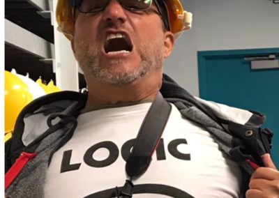 Steve Blum wearing construction hat ripping open outer shirt to reveal Logic shirt