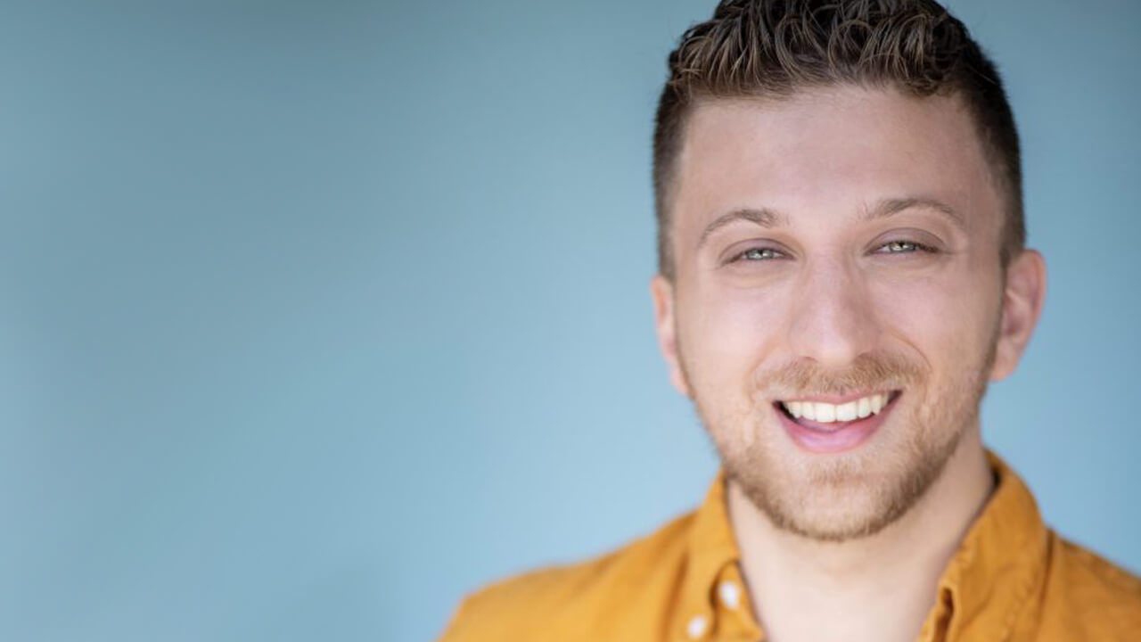 Headshot of Blumvox Studios team member Brandon Blum smiling in a light orange button-up shirt