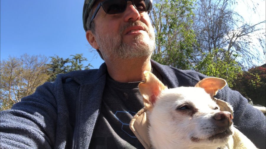 Steve Blum with Piddle the dog on his lap both looking out in the distance