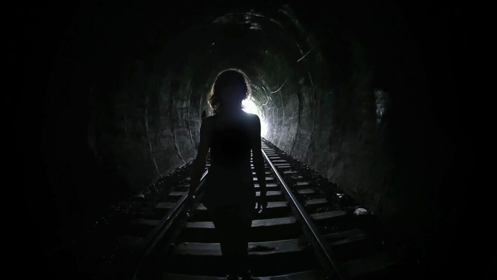 Woman walking out of a tunnel into the light