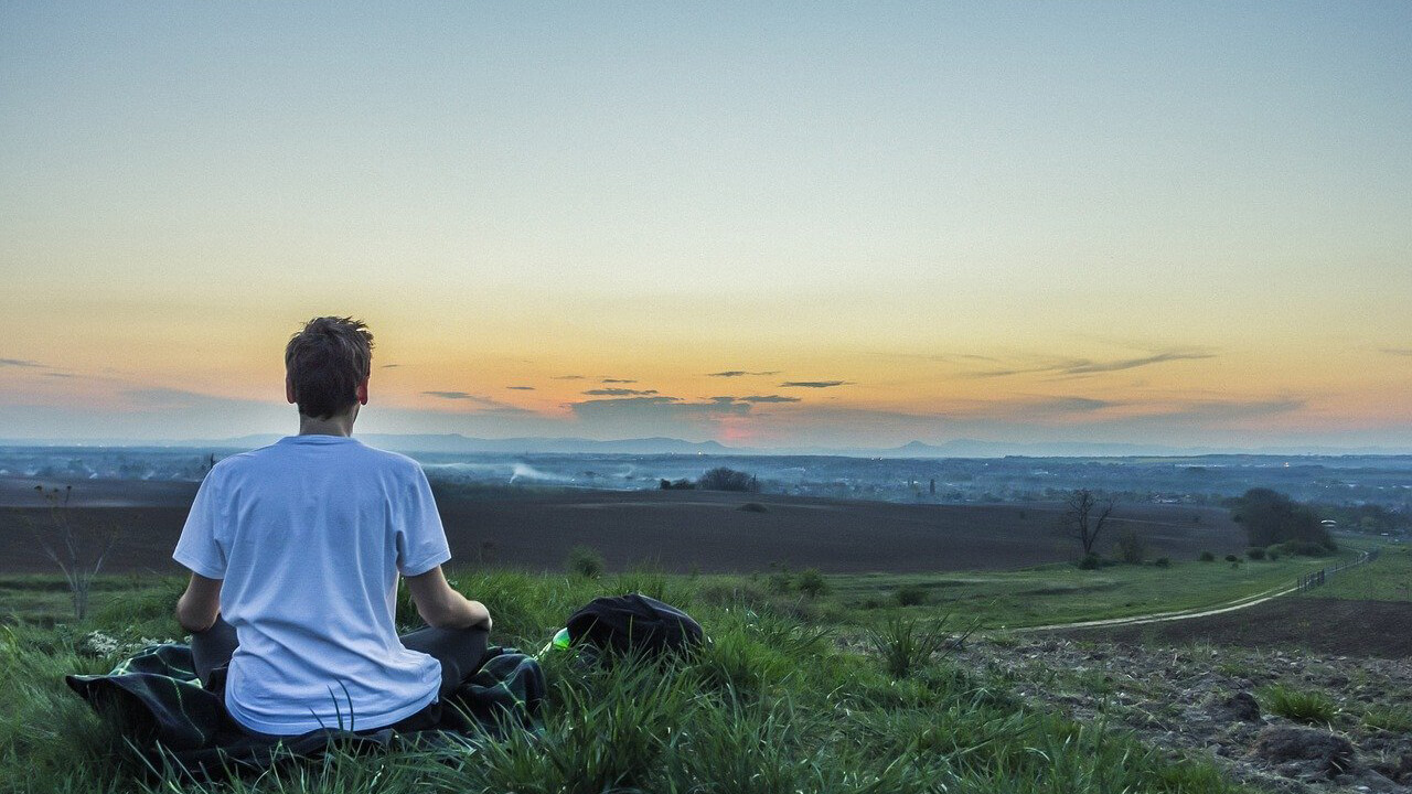 Person recalibrating by meditating in field