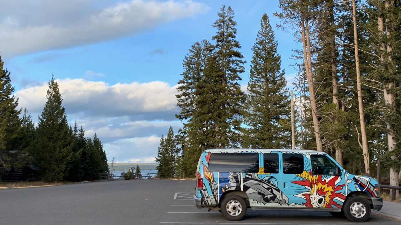 Image of Comic Van parked in parking lot surrounded by forest