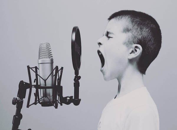 Black and white photo of a young boy yelling into a microphone