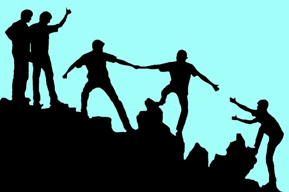Healthy Competition- Light blue background image with silhouette of people helping each other up a mountain